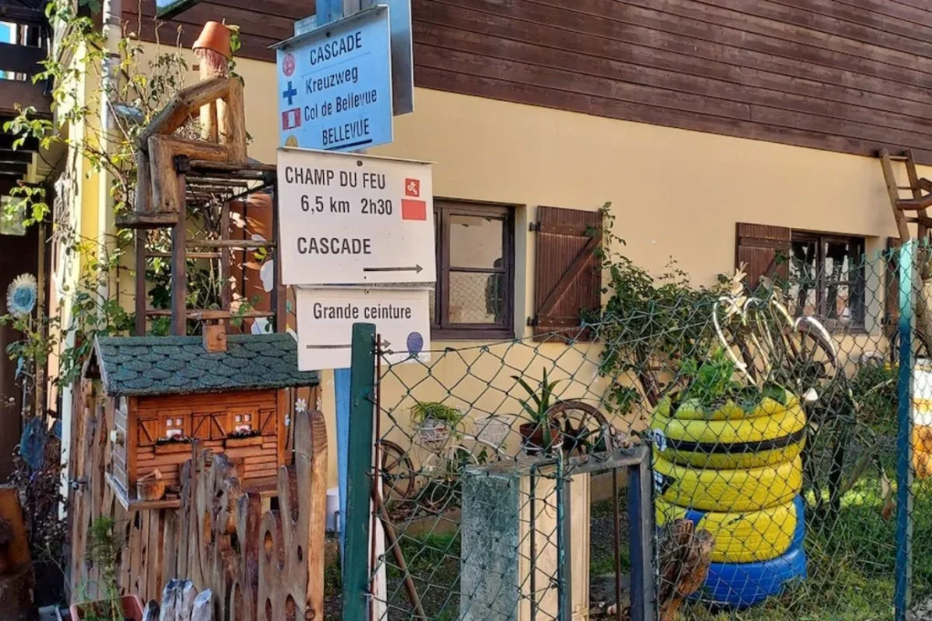 panneaux directionnels du Club Vosgien devant une maison de village indiquant la direction du Champ du Feu