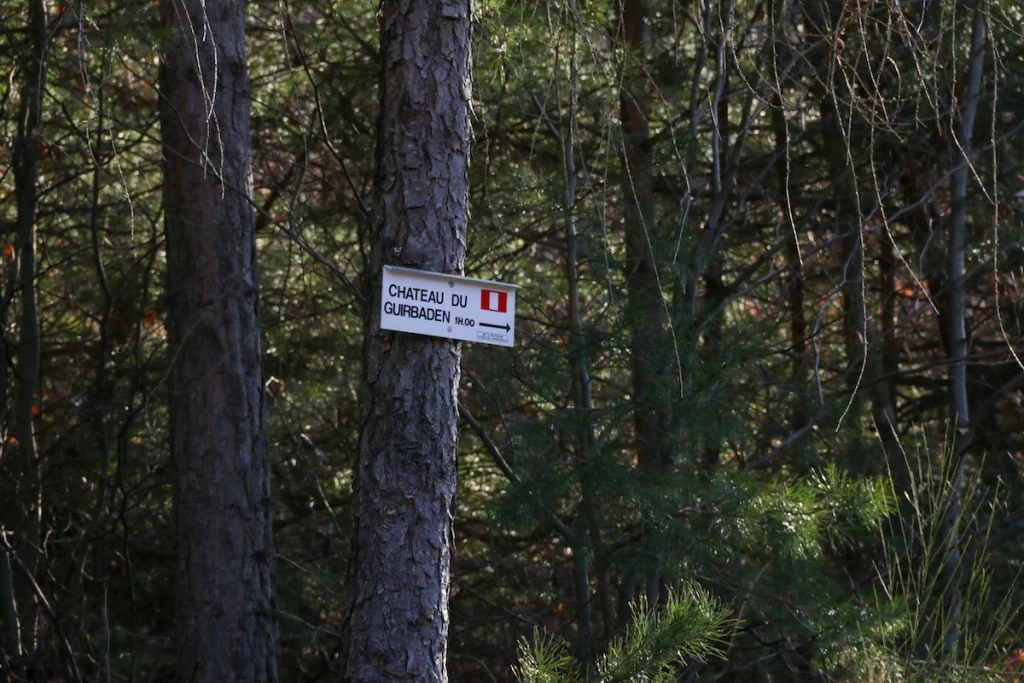 panneau directionnel du Club Vosgien sur un arbre indiquant la durée de la randonnée vers le Guirbaden