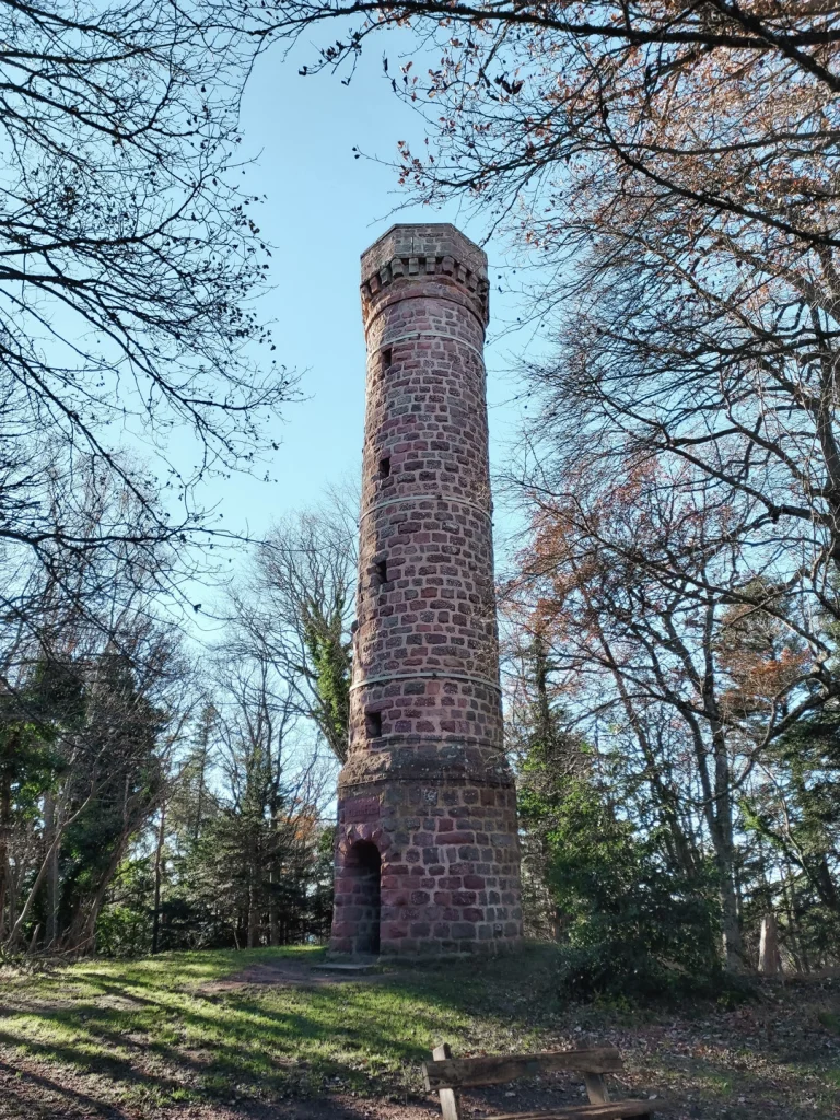 Une tour circulaire en grès rose entourée d'arbres au sommet du Heidenkopf