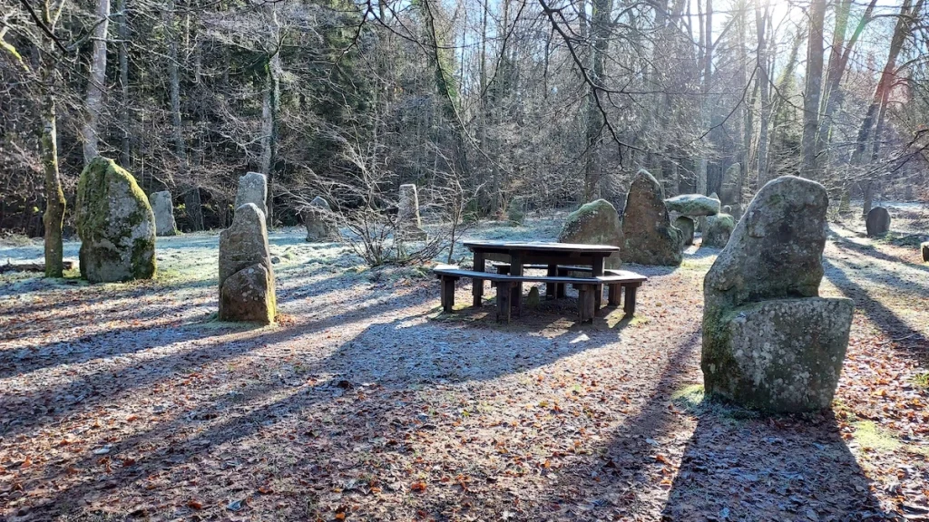 une table de pique-nique au milieu de pierres dressées et entourée d'arbres