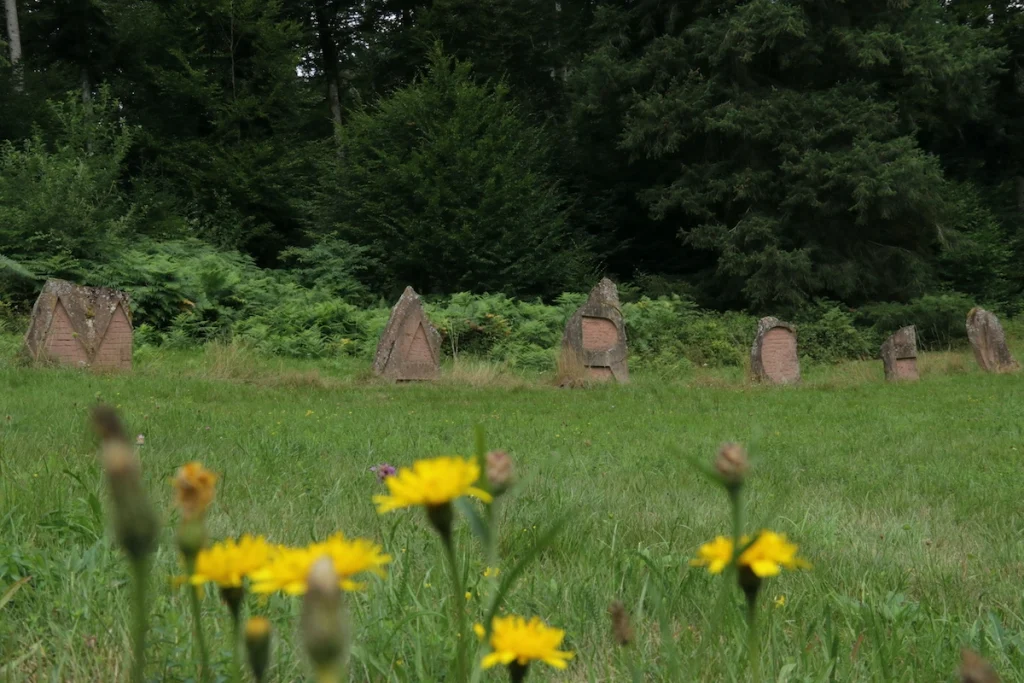 une sculpture en grès composée de lettres m a r c e l espacées, dans un pré à la lisière de la forêt sur les hauteurs de Lutzelhouse